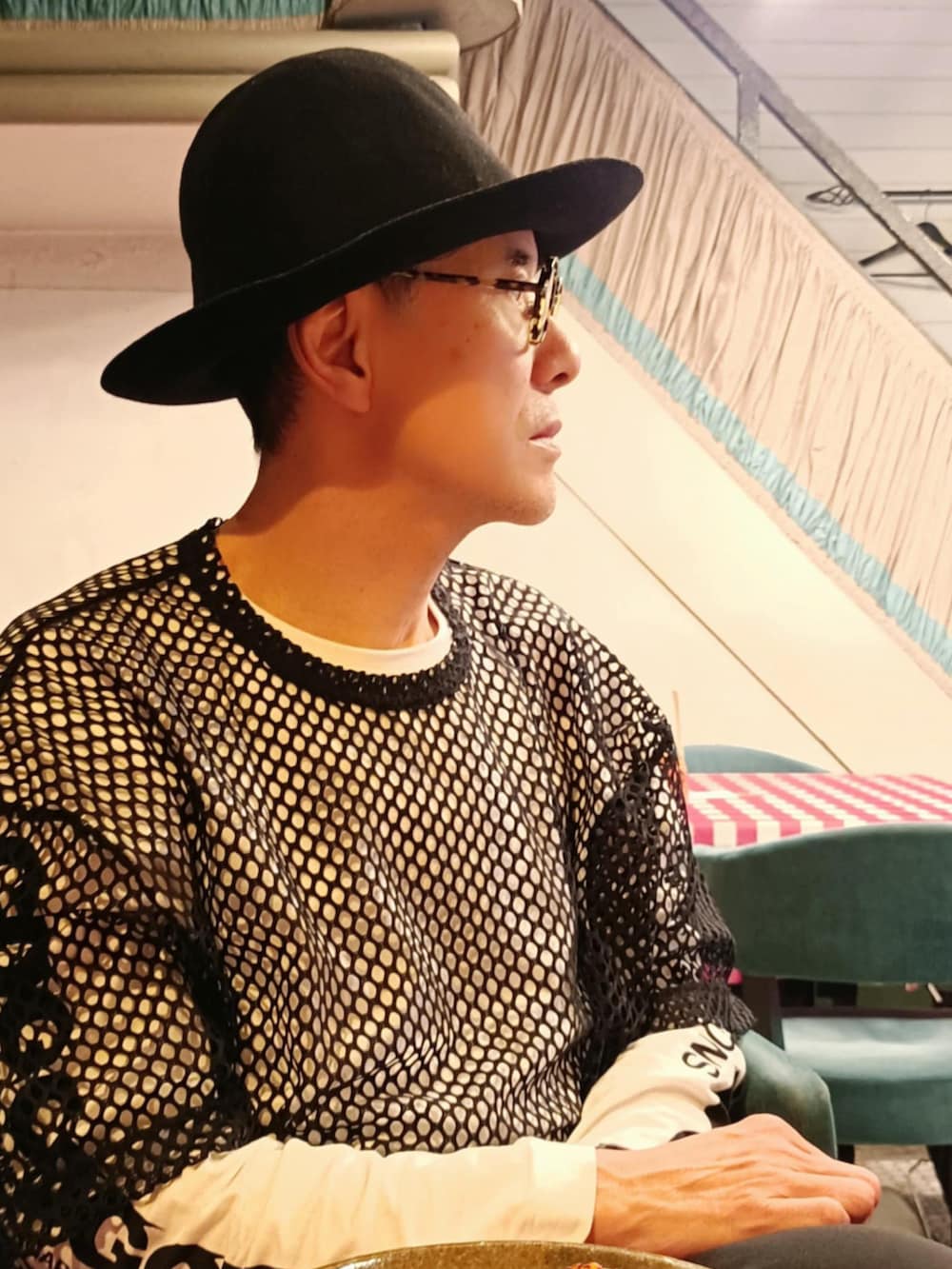 ホワイト系のスニーカー、ブラック系のポンチョ、ホワイト系のTシャツ/カットソーを着用したメンズの春コーディネートの3枚目の写真