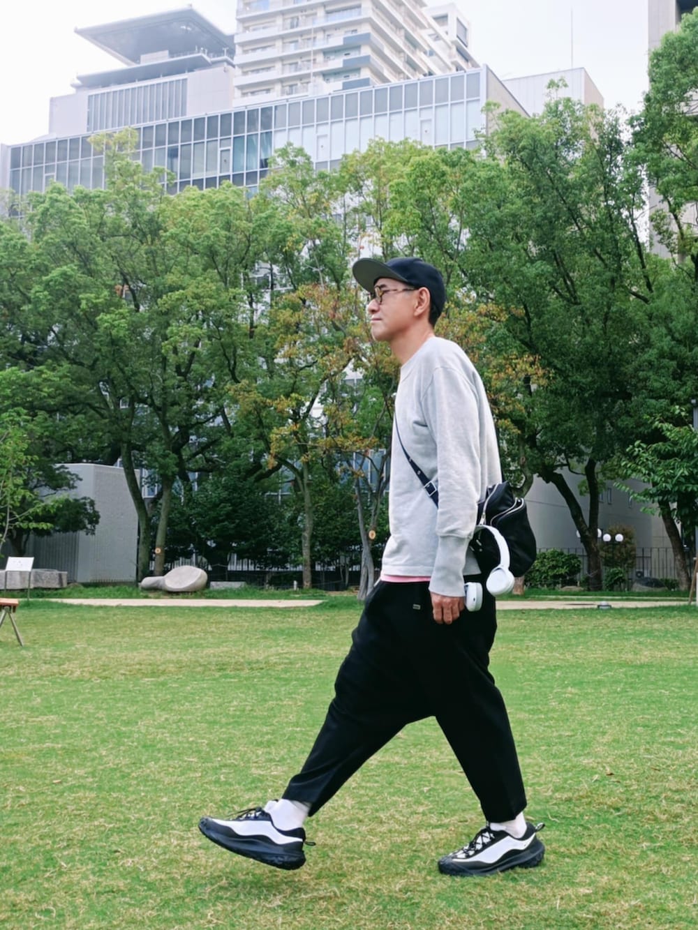 グレー系のTシャツ/カットソー、ホワイト系のスニーカー、ブラック系のキャップを着用したメンズの秋コーディネートの3枚目の写真