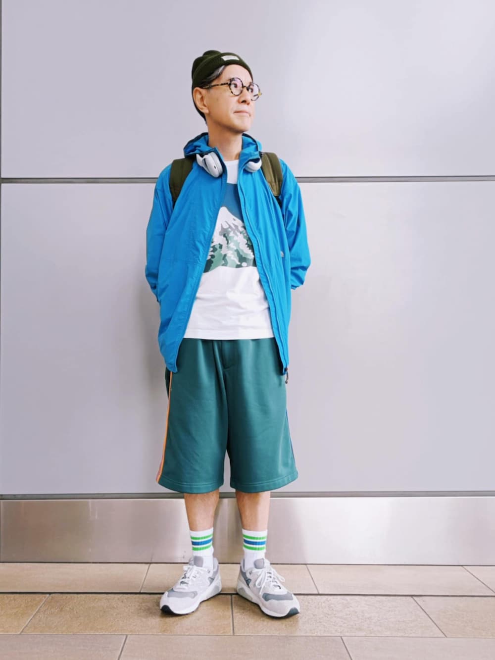 グリーン系のパンツ、ブルー系のマウンテンパーカー、グレー系のスニーカーを着用したメンズの秋コーディネートの3枚目の写真