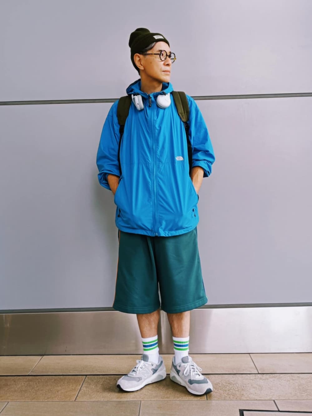 グリーン系のパンツ、ブルー系のマウンテンパーカー、グレー系のスニーカーを着用したメンズの秋コーディネートの2枚目の写真