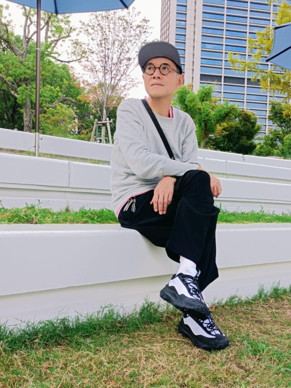 グレー系のTシャツ/カットソー、ホワイト系のスニーカー、ブラック系のキャップを着用したメンズの秋コーディネートの2枚目の写真