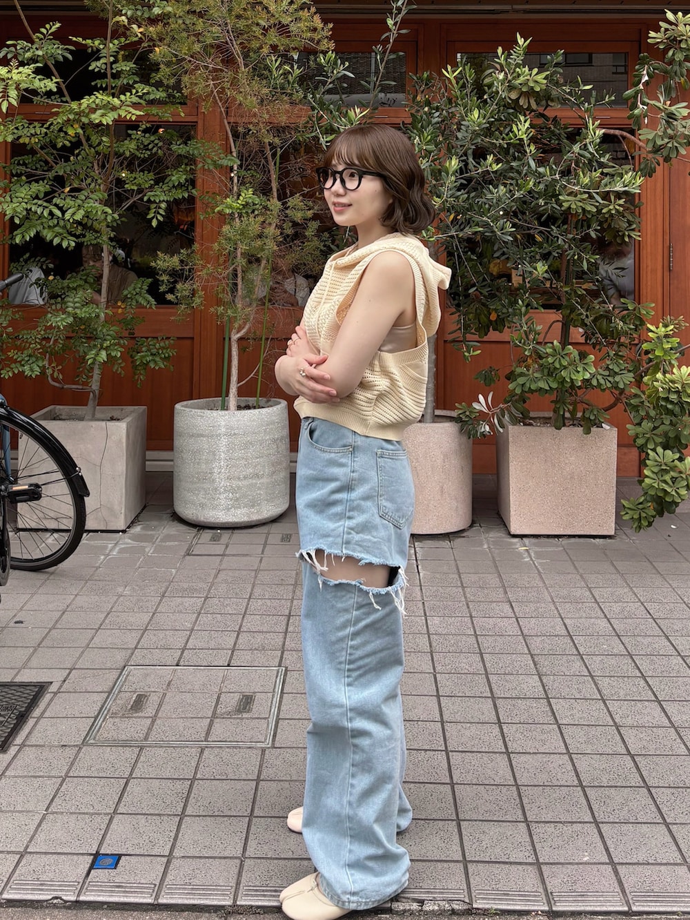 ホワイト系のベスト、ブルー系のデニムパンツ、ホワイト系のパンプスを着用したレディースの夏コーディネートの2枚目の写真