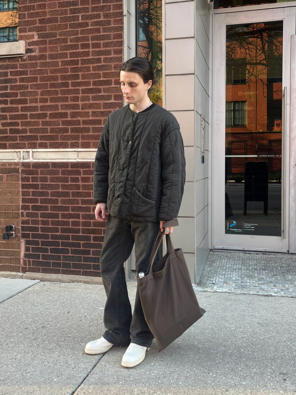 グレー系のノーカラーコート、グレー系のデニムパンツ、ホワイト系のブーツを着用したメンズの春コーディネートの2枚目の写真