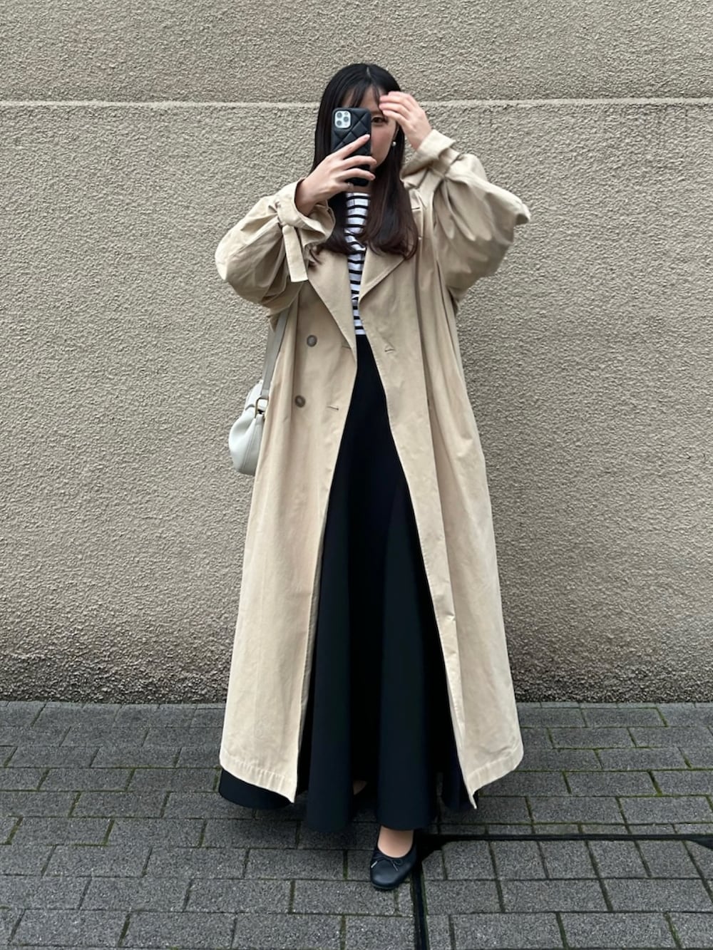 ホワイト系のショルダーバッグ、ブラック系のスカート、ベージュ系のトレンチコートを着用したレディースの春コーディネートの3枚目の写真