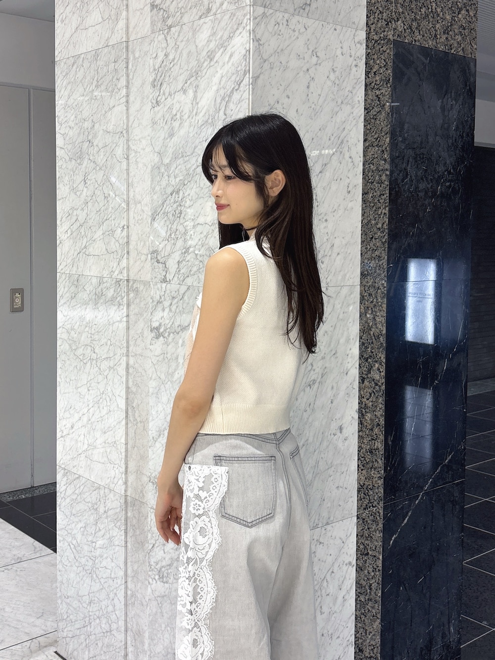 グレー系のデニムパンツ、ホワイト系のニット/セーター、ホワイト系のサンダルを着用したレディースの夏コーディネートの6枚目の写真