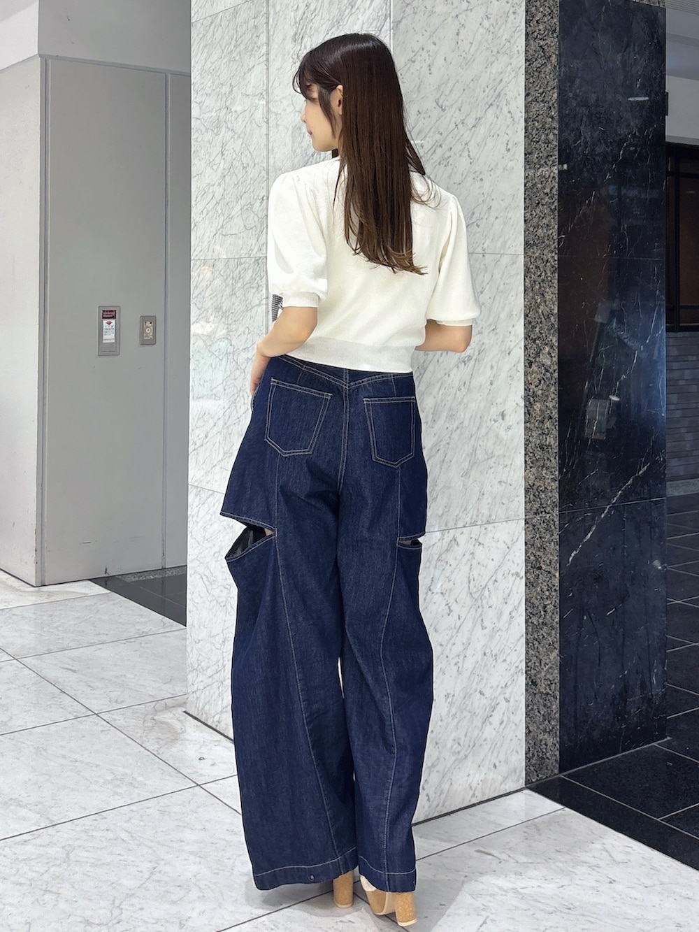 ブルー系のデニムパンツ、ホワイト系のサンダル、ホワイト系のニット/セーターを着用したレディースの春コーディネートの3枚目の写真
