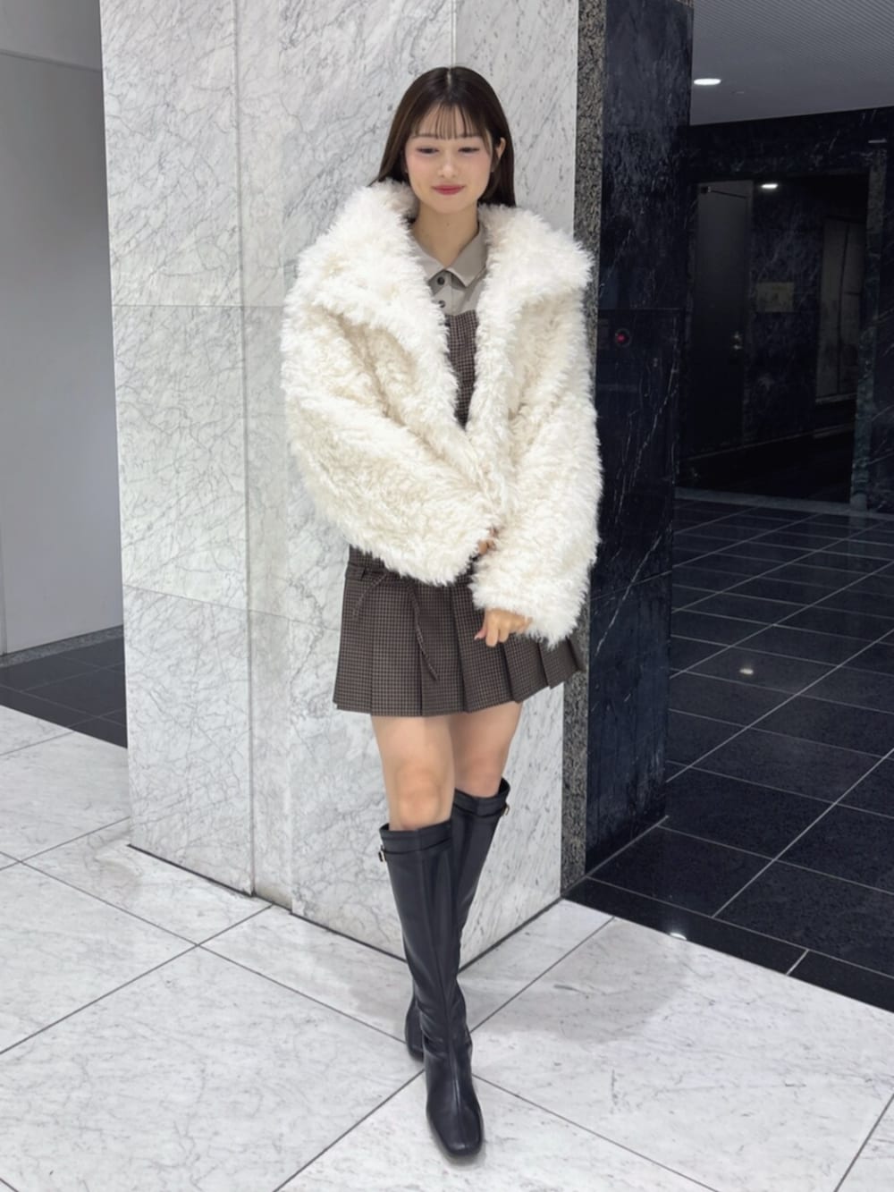 ブラック系のブーツ、ホワイト系のブルゾンを着用したレディースの秋コーディネートの3枚目の写真