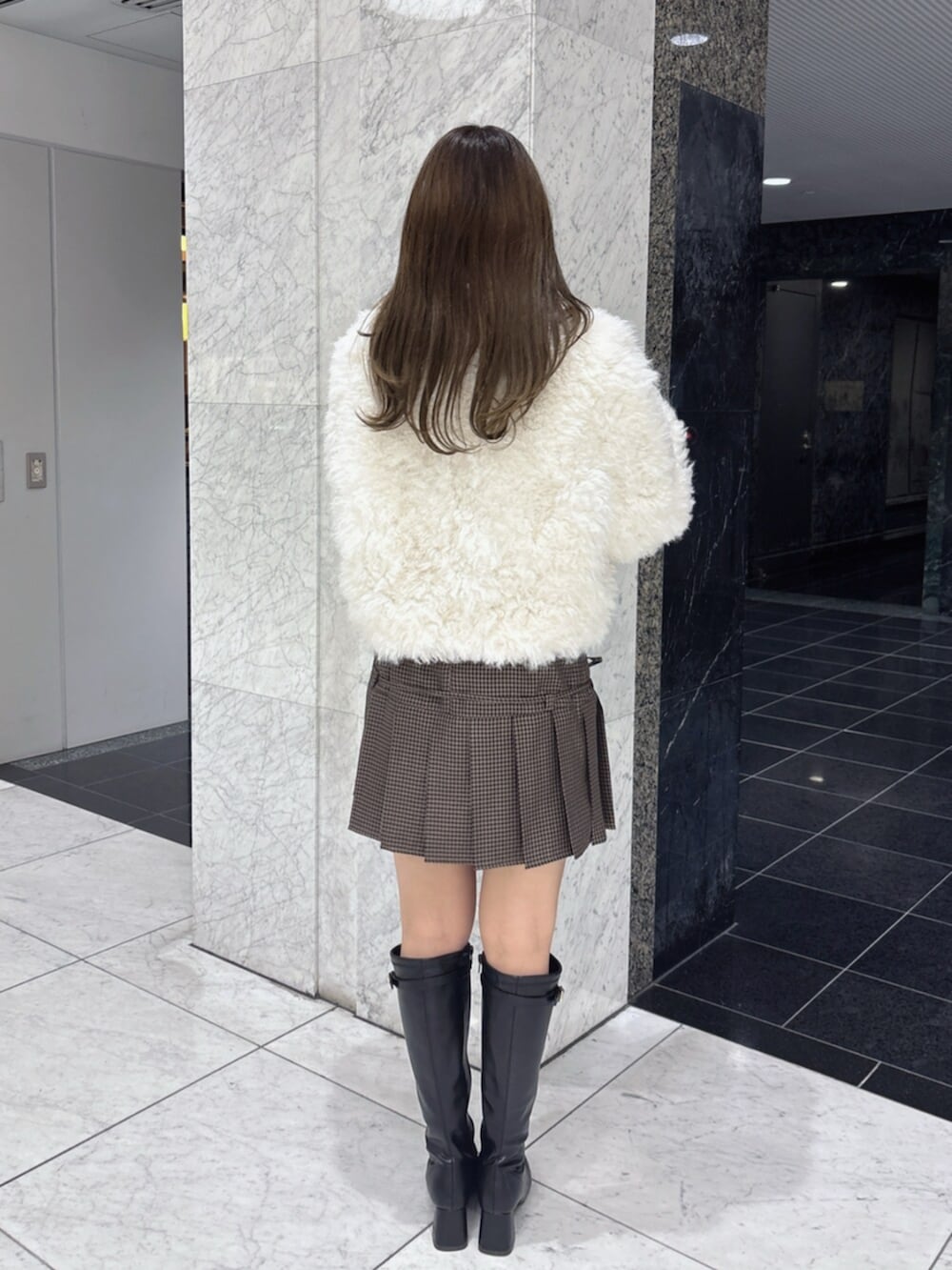 ブラック系のブーツ、ホワイト系のブルゾンを着用したレディースの秋コーディネートの5枚目の写真