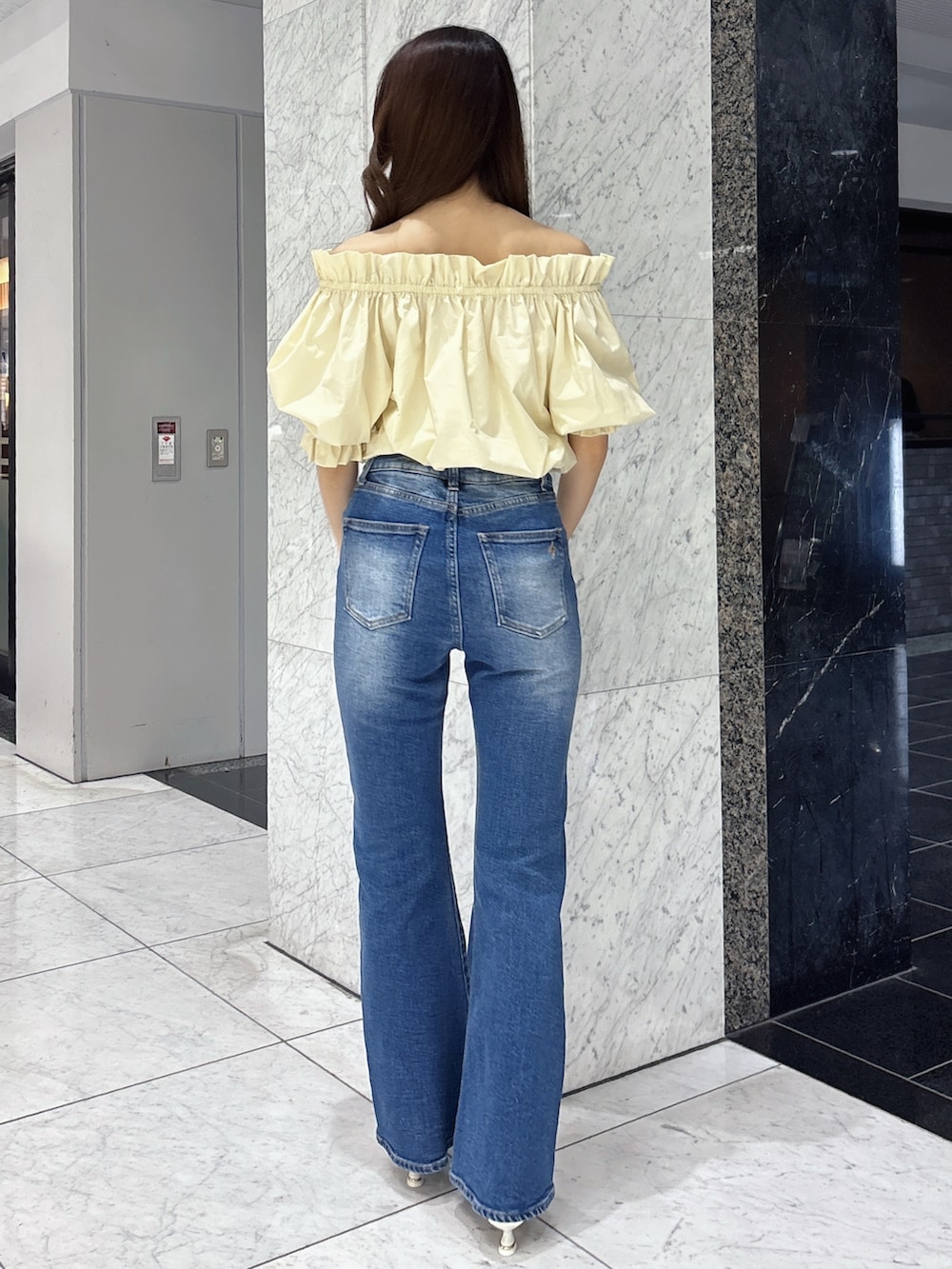 ブルー系のデニムパンツ、イエロー系のシャツ/ブラウス、ホワイト系のパンプスを着用したレディースの春コーディネートの3枚目の写真