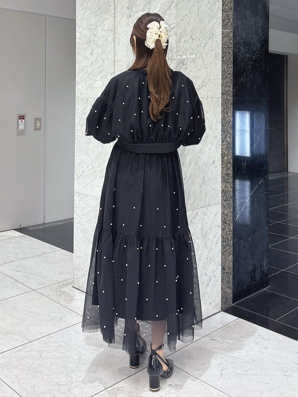 ブラック系のワンピース、ブラック系のブルゾン、ブラック系のサンダルを着用したレディースの春コーディネートの5枚目の写真