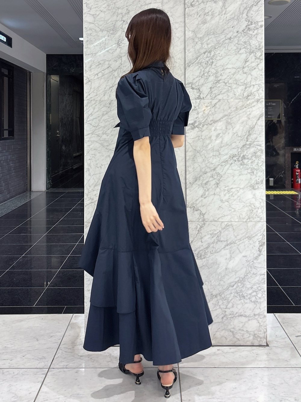 ブルー系のワンピース、ホワイト系のハンドバッグ、ブラック系のパンプスを着用したレディースの春コーディネートの4枚目の写真