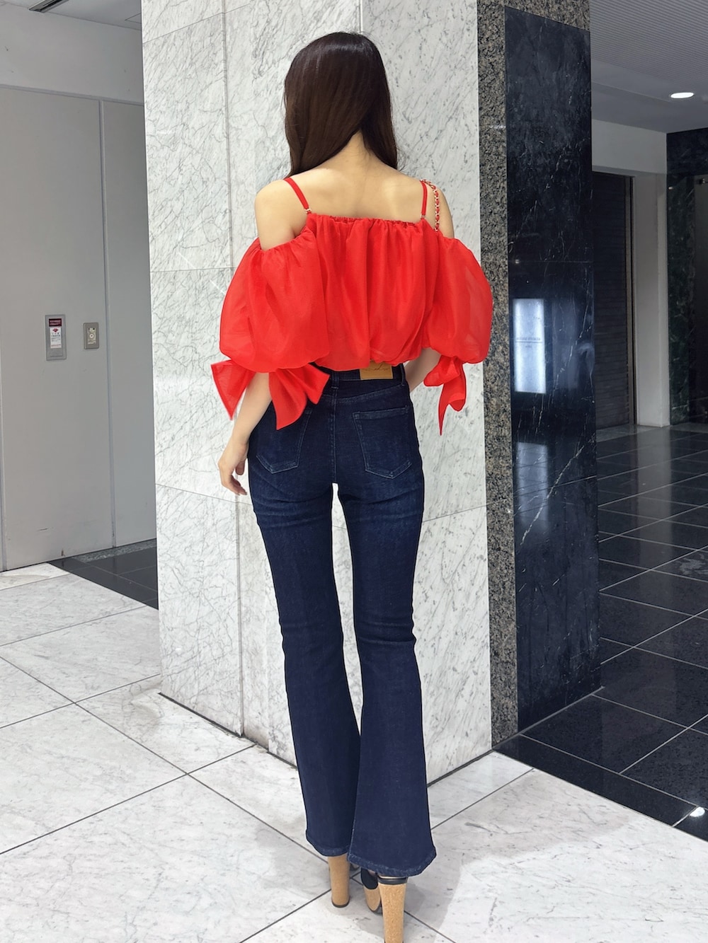 ブルー系のデニムパンツ、レッド系のシャツ/ブラウス、レッド系のショルダーバッグを着用したレディースの春コーディネートの4枚目の写真