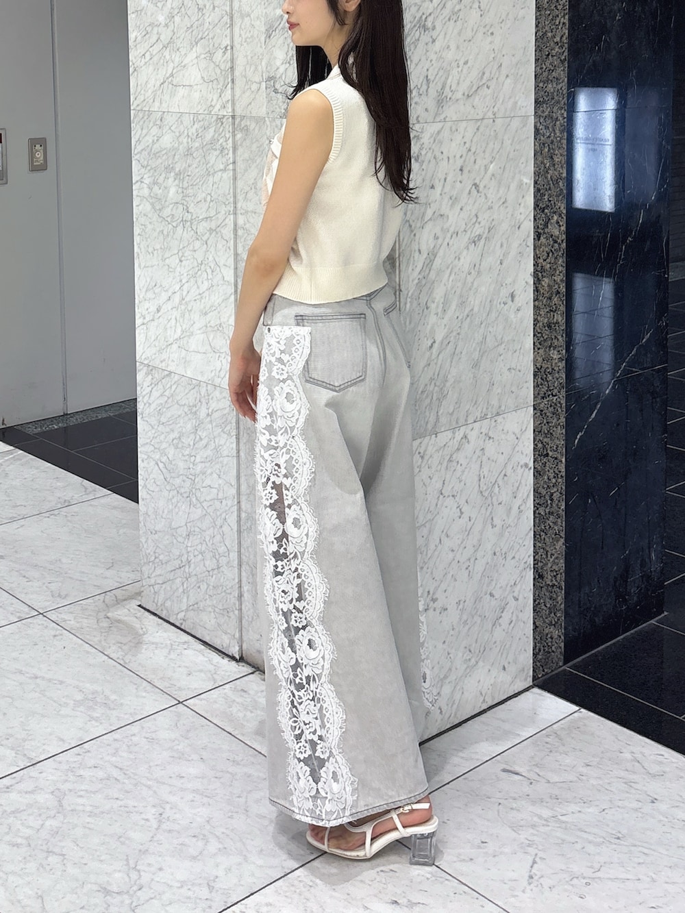 グレー系のデニムパンツ、ホワイト系のニット/セーター、ホワイト系のサンダルを着用したレディースの夏コーディネートの3枚目の写真