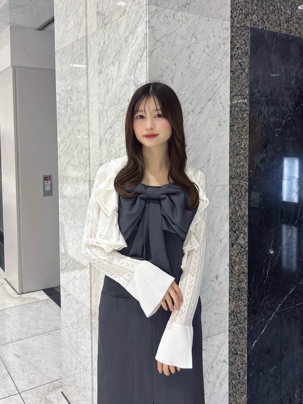 グレー系のワンピース、ホワイト系のカーディガン/ボレロ、ブラック系のパンプスを着用したレディースの春コーディネートの4枚目の写真