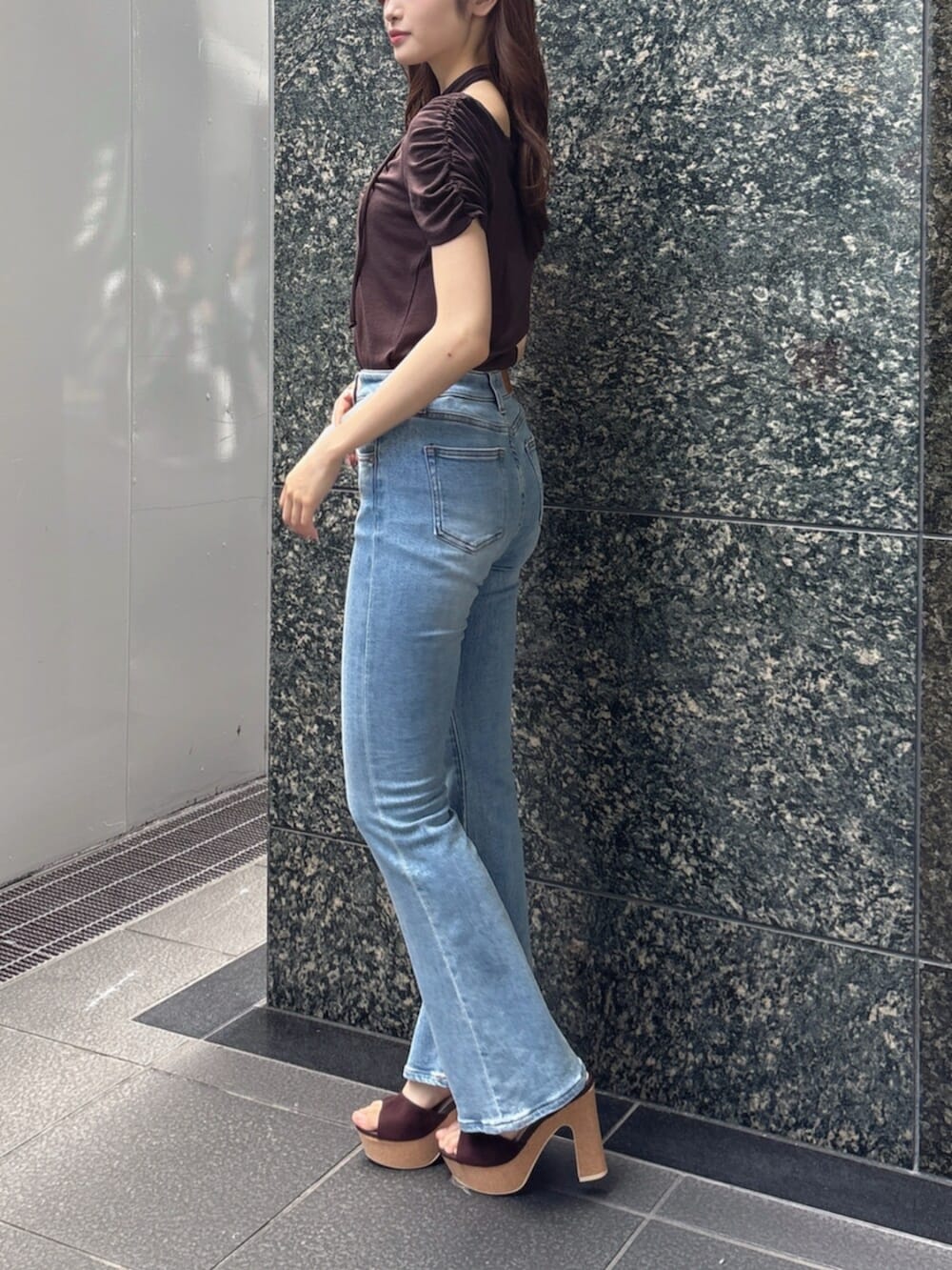 ブルー系のデニムパンツ、ブラウン系のTシャツ/カットソー、ブラウン系のサンダルを着用したレディースの春コーディネートの3枚目の写真