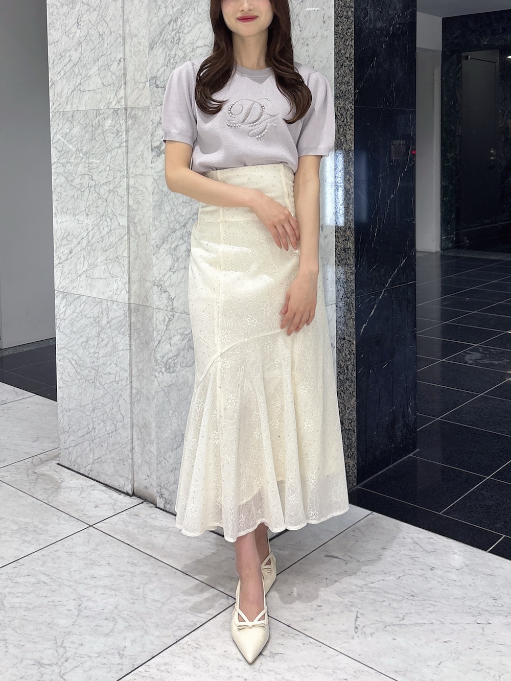 ホワイト系のスカート、グレー系のニット/セーター、ホワイト系のパンプスを着用したレディースの春コーディネートの2枚目の写真