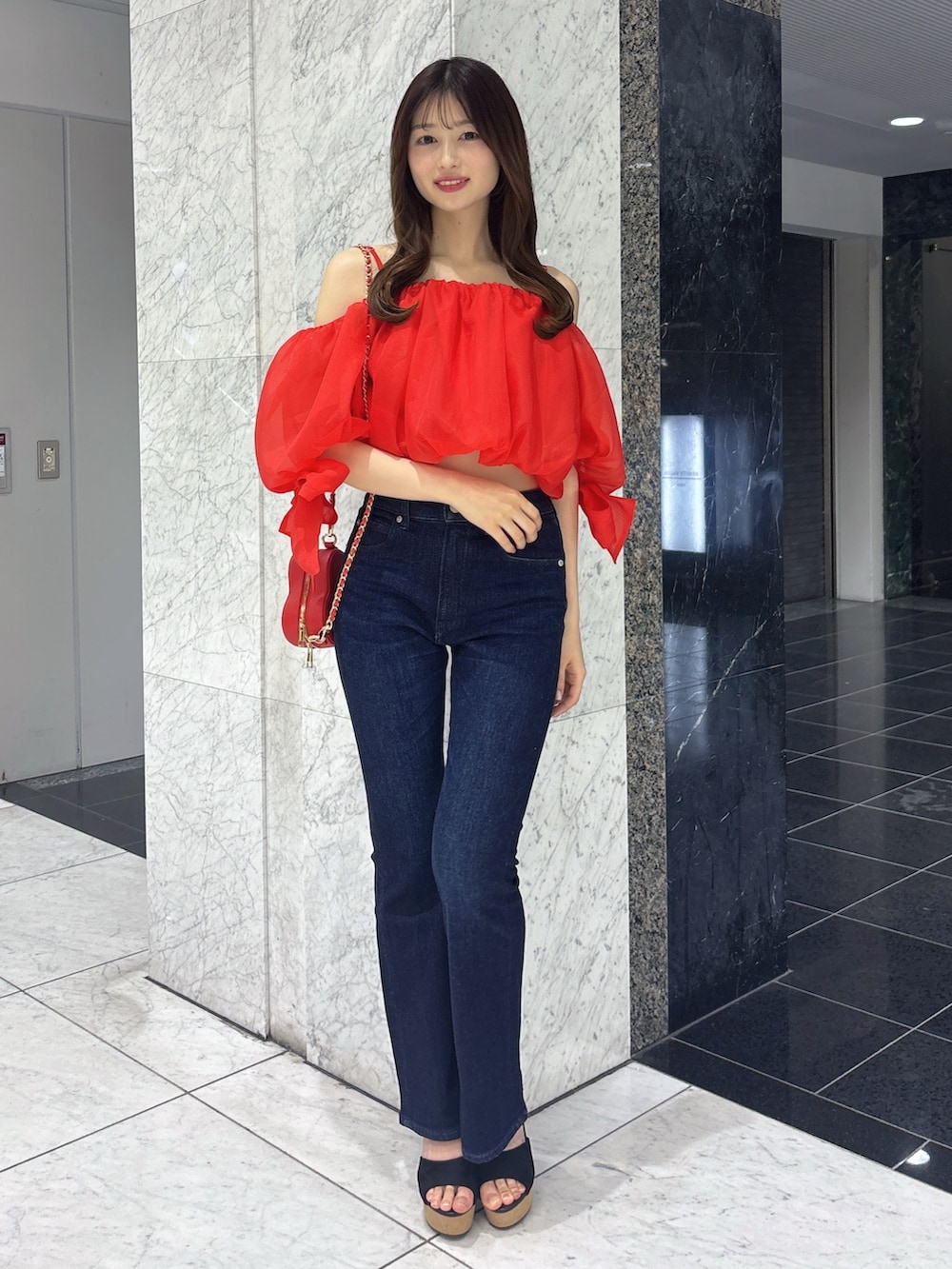 ブルー系のデニムパンツ、レッド系のシャツ/ブラウス、レッド系のショルダーバッグを着用したレディースの春コーディネートの2枚目の写真