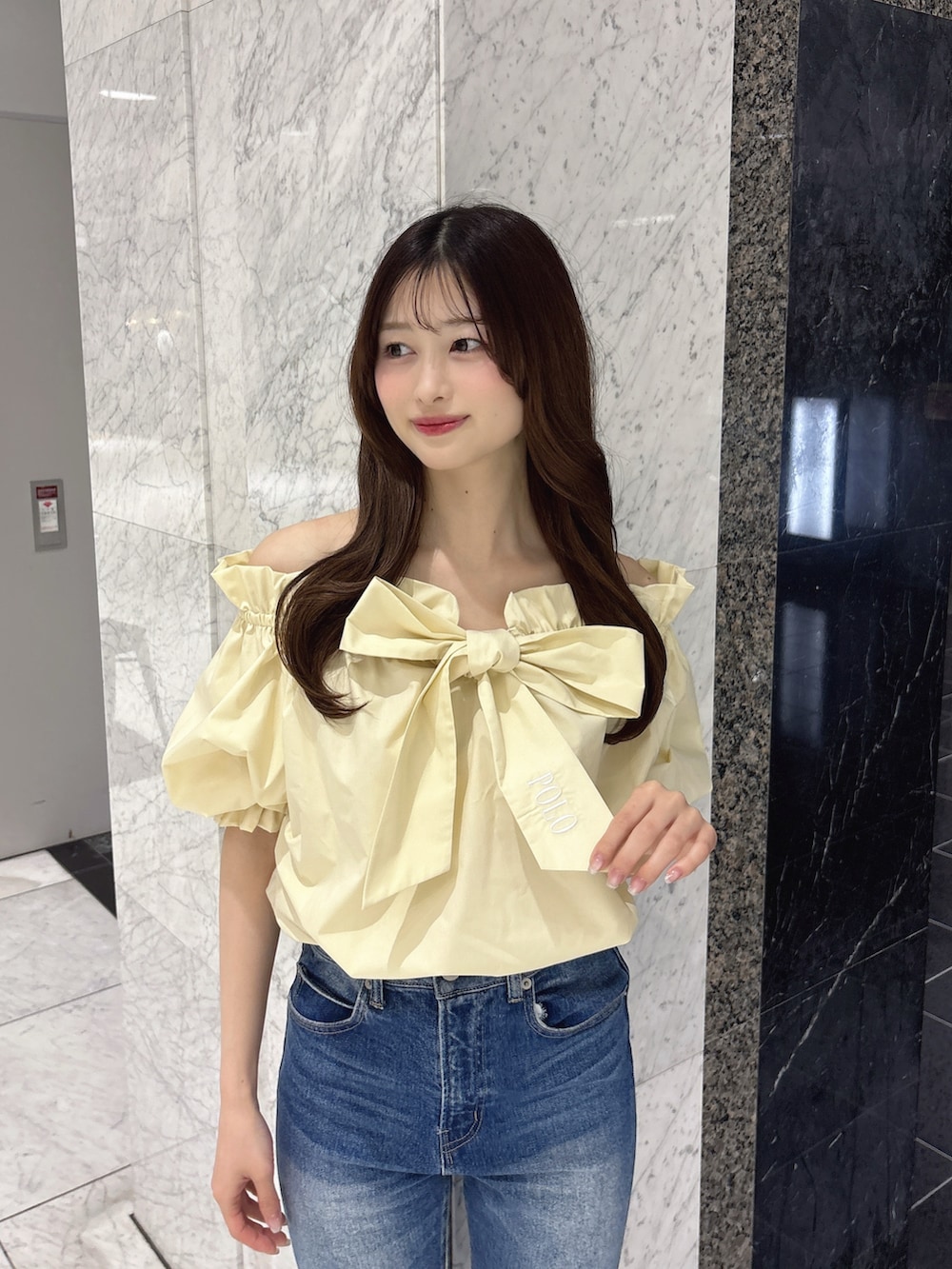 ブルー系のデニムパンツ、イエロー系のシャツ/ブラウス、ホワイト系のパンプスを着用したレディースの春コーディネートの4枚目の写真