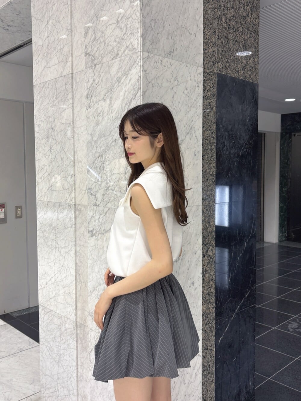 ブラック系のサンダル、グレー系のスカート、ホワイト系のTシャツ/カットソーを着用したレディースの夏コーディネートの6枚目の写真