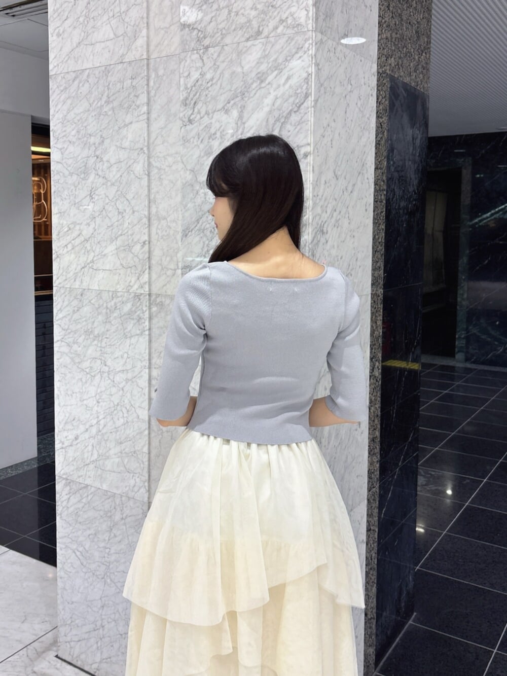 ホワイト系のスカート、グレー系のニット/セーター、ホワイト系のパンプスを着用したレディースの夏コーディネートの7枚目の写真