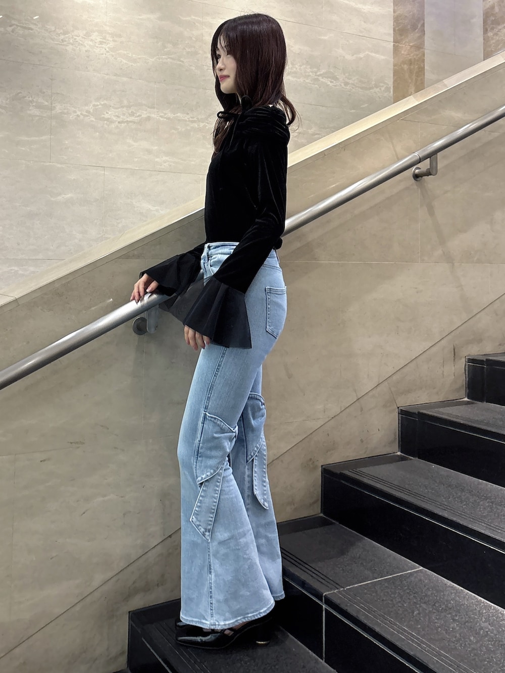 ブルー系のデニムパンツ、ブラック系のTシャツ/カットソー、ブラック系のサンダルを着用したレディースの冬コーディネートの3枚目の写真