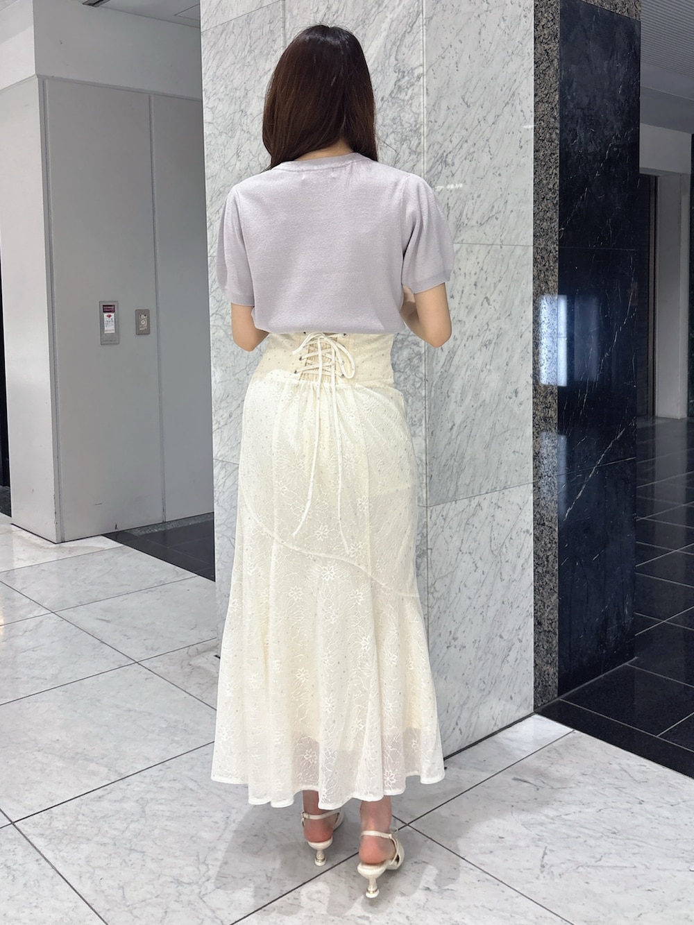 ホワイト系のスカート、グレー系のニット/セーター、ホワイト系のパンプスを着用したレディースの春コーディネートの4枚目の写真