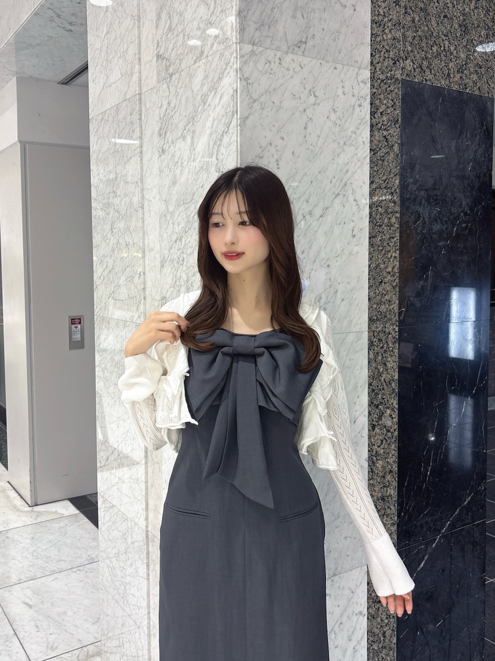 グレー系のワンピース、ホワイト系のカーディガン/ボレロ、ブラック系のパンプスを着用したレディースの春コーディネートの5枚目の写真