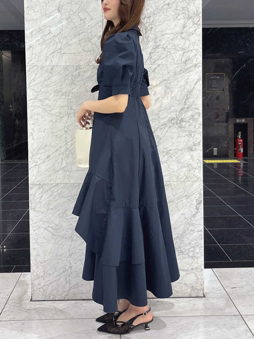 ブルー系のワンピース、ホワイト系のハンドバッグ、ブラック系のパンプスを着用したレディースの春コーディネートの3枚目の写真