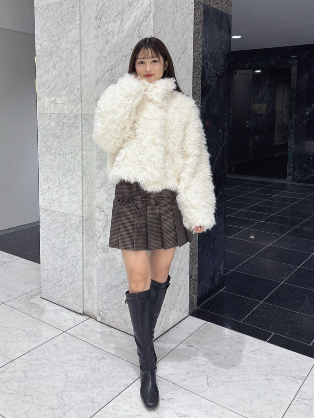 ブラック系のブーツ、ホワイト系のブルゾンを着用したレディースの秋コーディネートの7枚目の写真