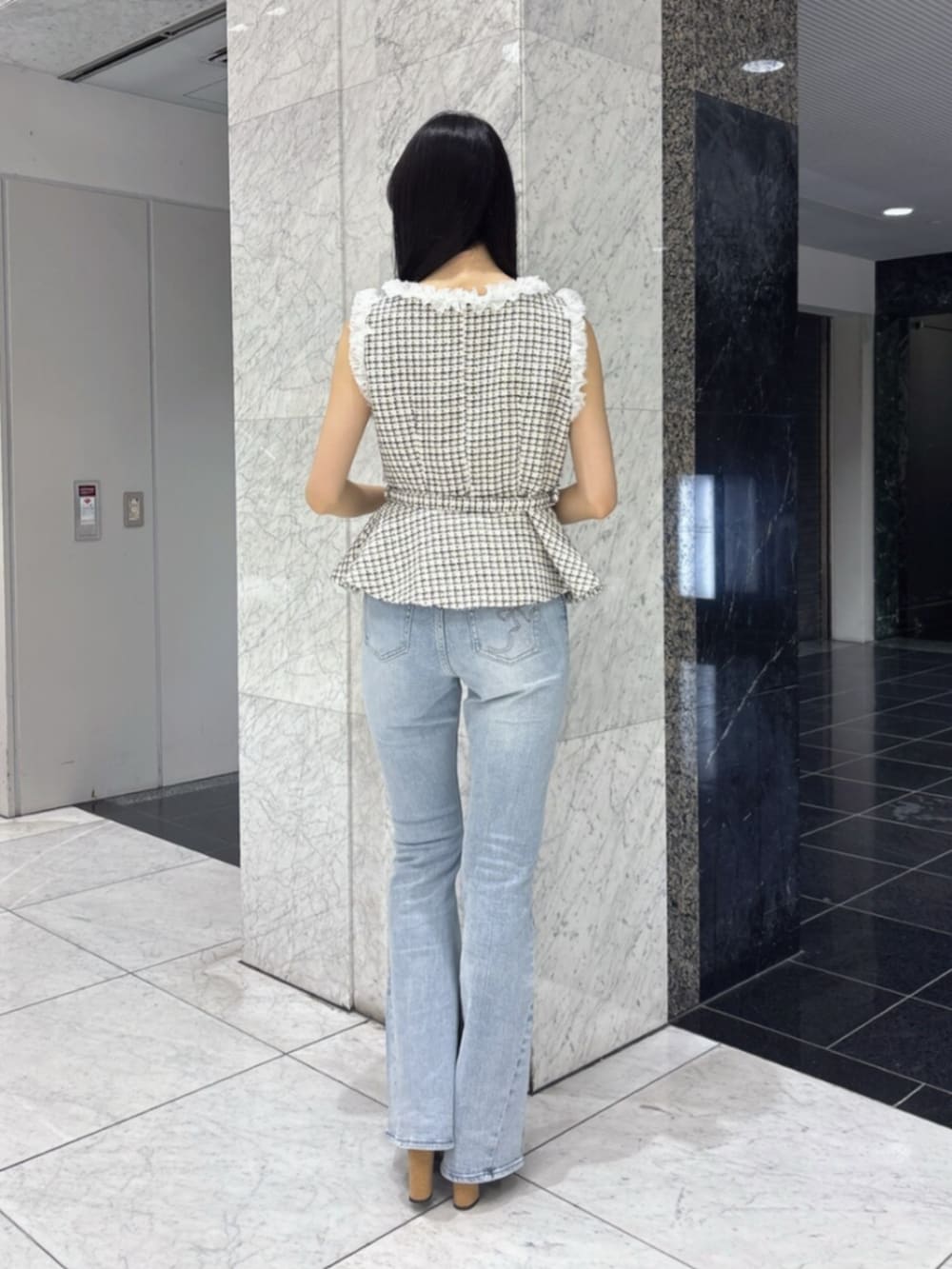 ブラック系のサンダル、ホワイト系のベスト、ブルー系のデニムパンツを着用したレディースの夏コーディネートの3枚目の写真