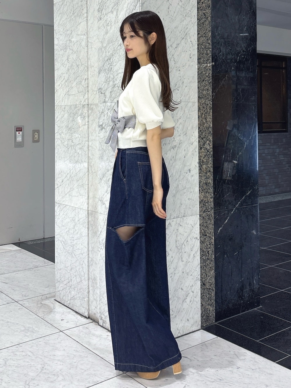ブルー系のデニムパンツ、ホワイト系のサンダル、ホワイト系のニット/セーターを着用したレディースの春コーディネートの2枚目の写真