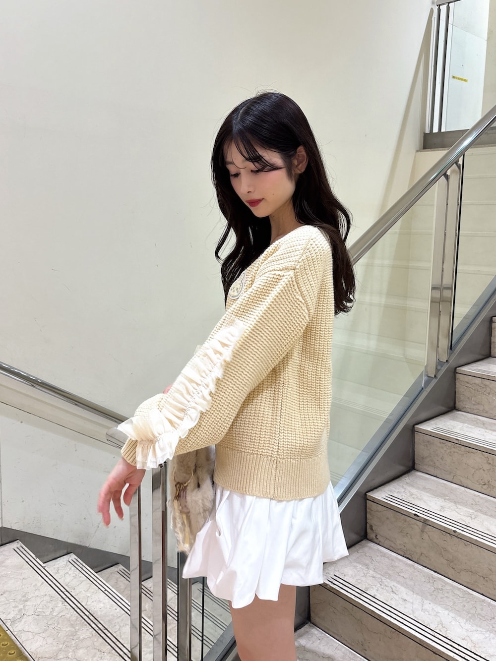 ホワイト系のスカート、ホワイト系のブーツ、イエロー系のハンドバッグを着用したレディースの秋コーディネートの5枚目の写真