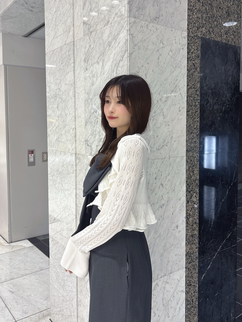 グレー系のワンピース、ホワイト系のカーディガン/ボレロ、ブラック系のパンプスを着用したレディースの春コーディネートの6枚目の写真