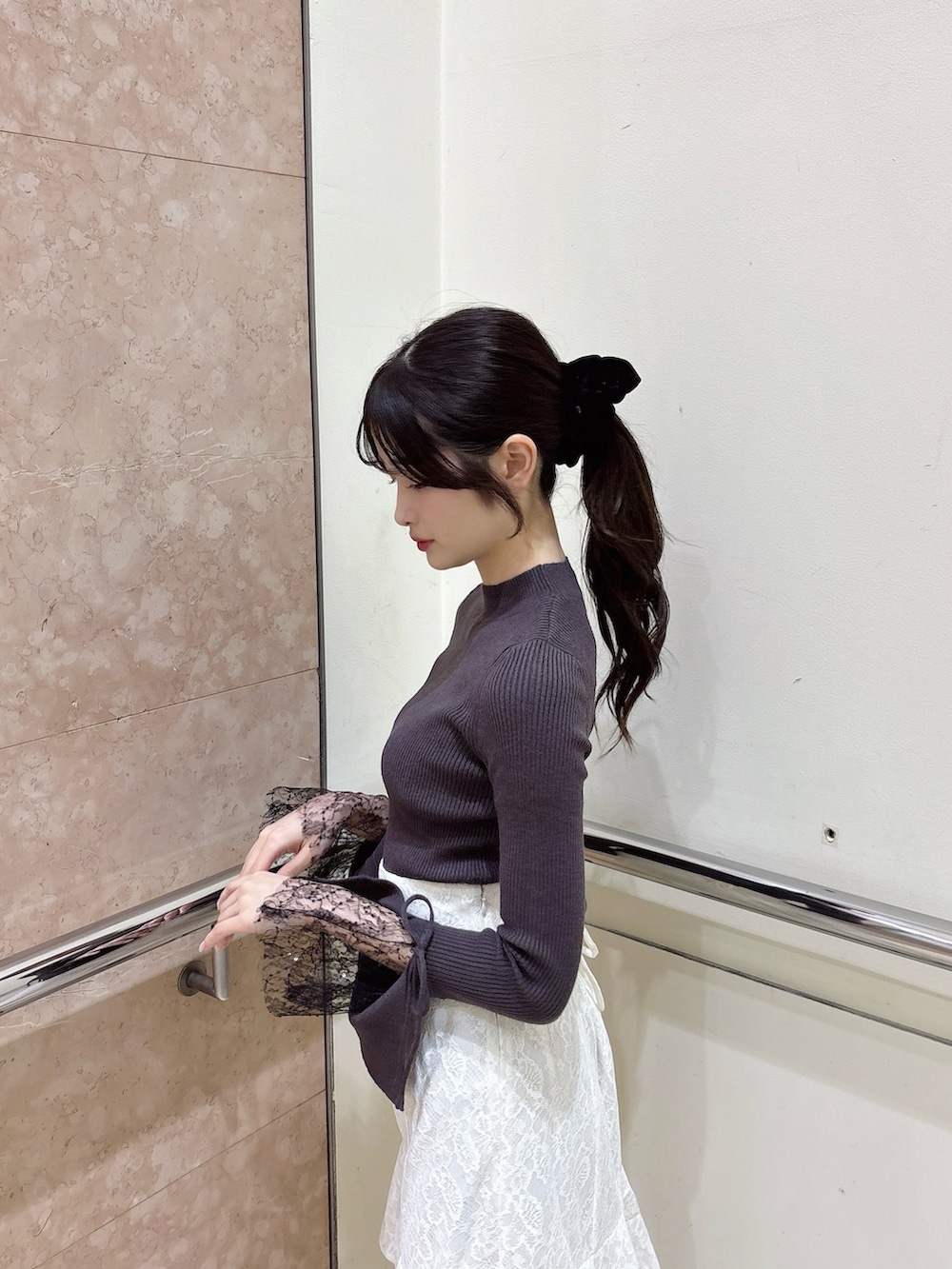 グレー系のニット/セーター、ホワイト系のスカート、ホワイト系のブーツを着用したレディースの秋コーディネートの5枚目の写真