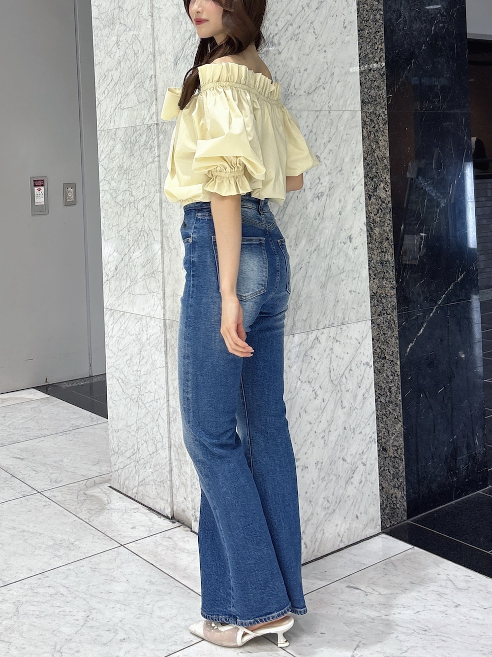 ブルー系のデニムパンツ、イエロー系のシャツ/ブラウス、ホワイト系のパンプスを着用したレディースの春コーディネートの2枚目の写真