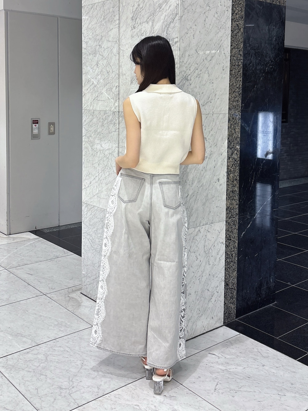 グレー系のデニムパンツ、ホワイト系のニット/セーター、ホワイト系のサンダルを着用したレディースの夏コーディネートの4枚目の写真