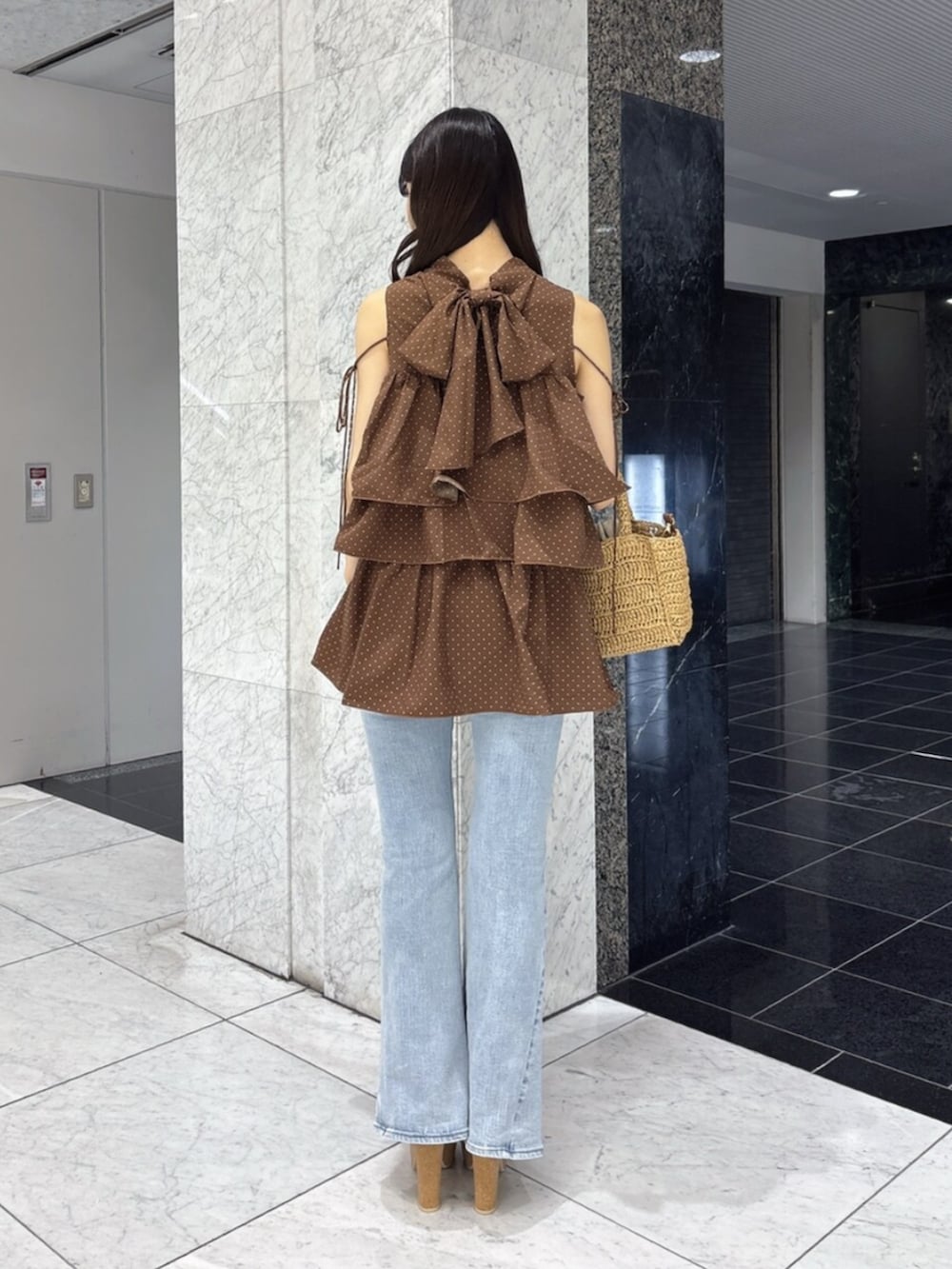 ホワイト系のサンダル、ブルー系のデニムパンツ、ブラウン系のかごバッグを着用したレディースの夏コーディネートの3枚目の写真