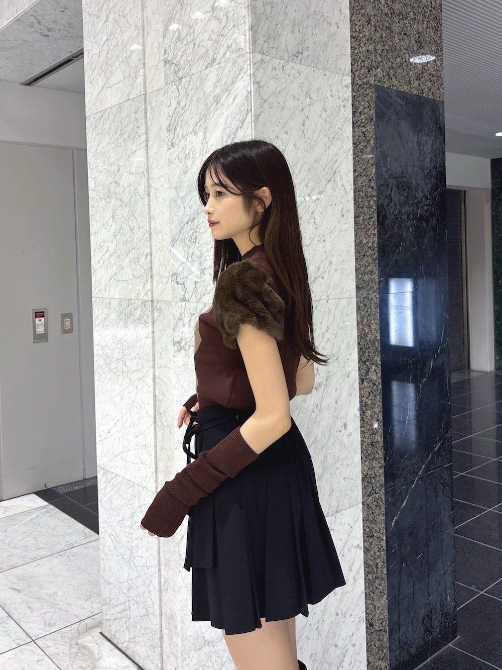 ブラウン系のニット/セーター、ブラック系のスカート、ブラック系のブーツを着用したレディースの秋コーディネートの5枚目の写真