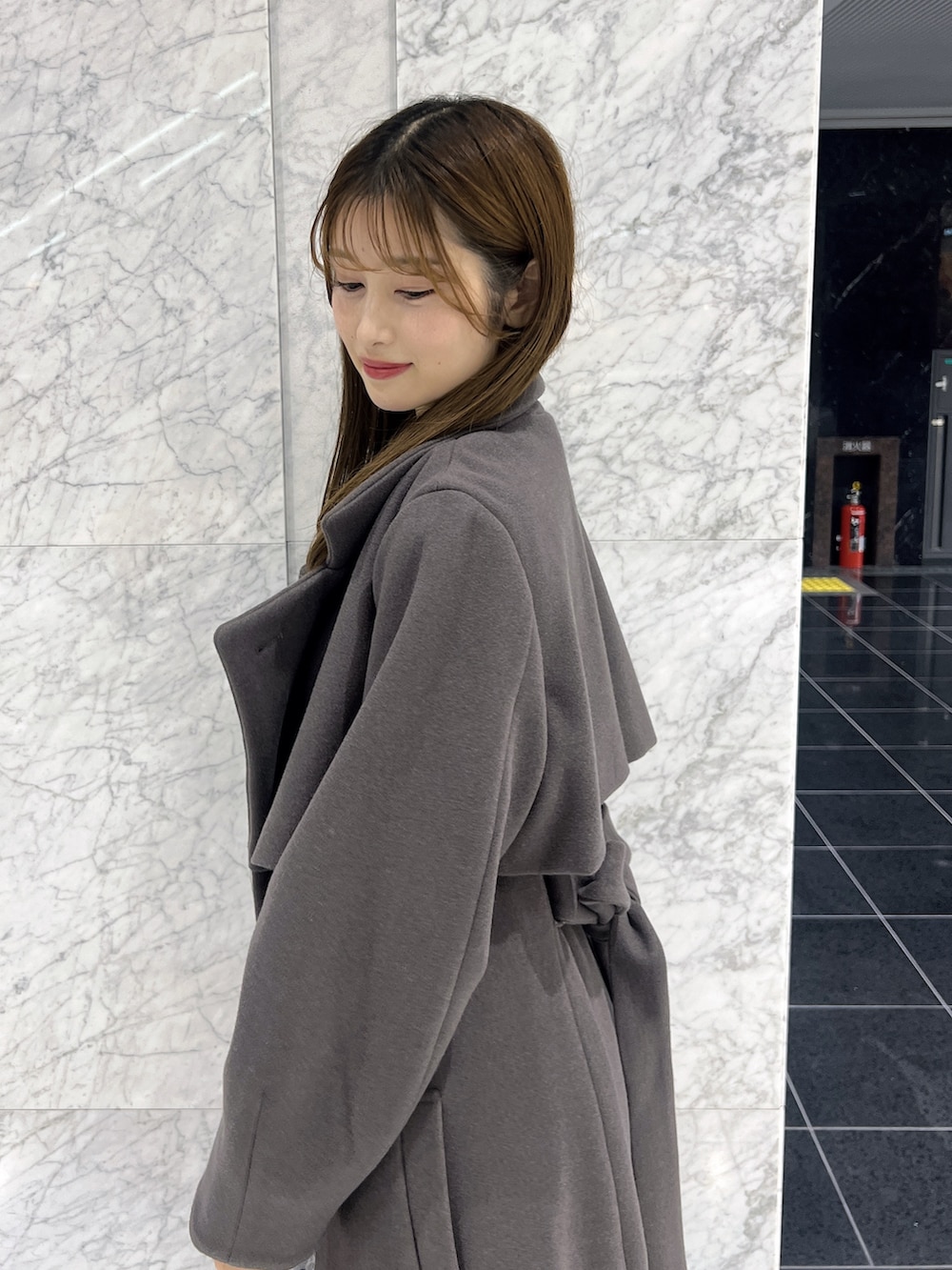 ブラック系のワンピース、ブラウン系のトレンチコート、ブラック系のブーツを着用したレディースの秋コーディネートの5枚目の写真