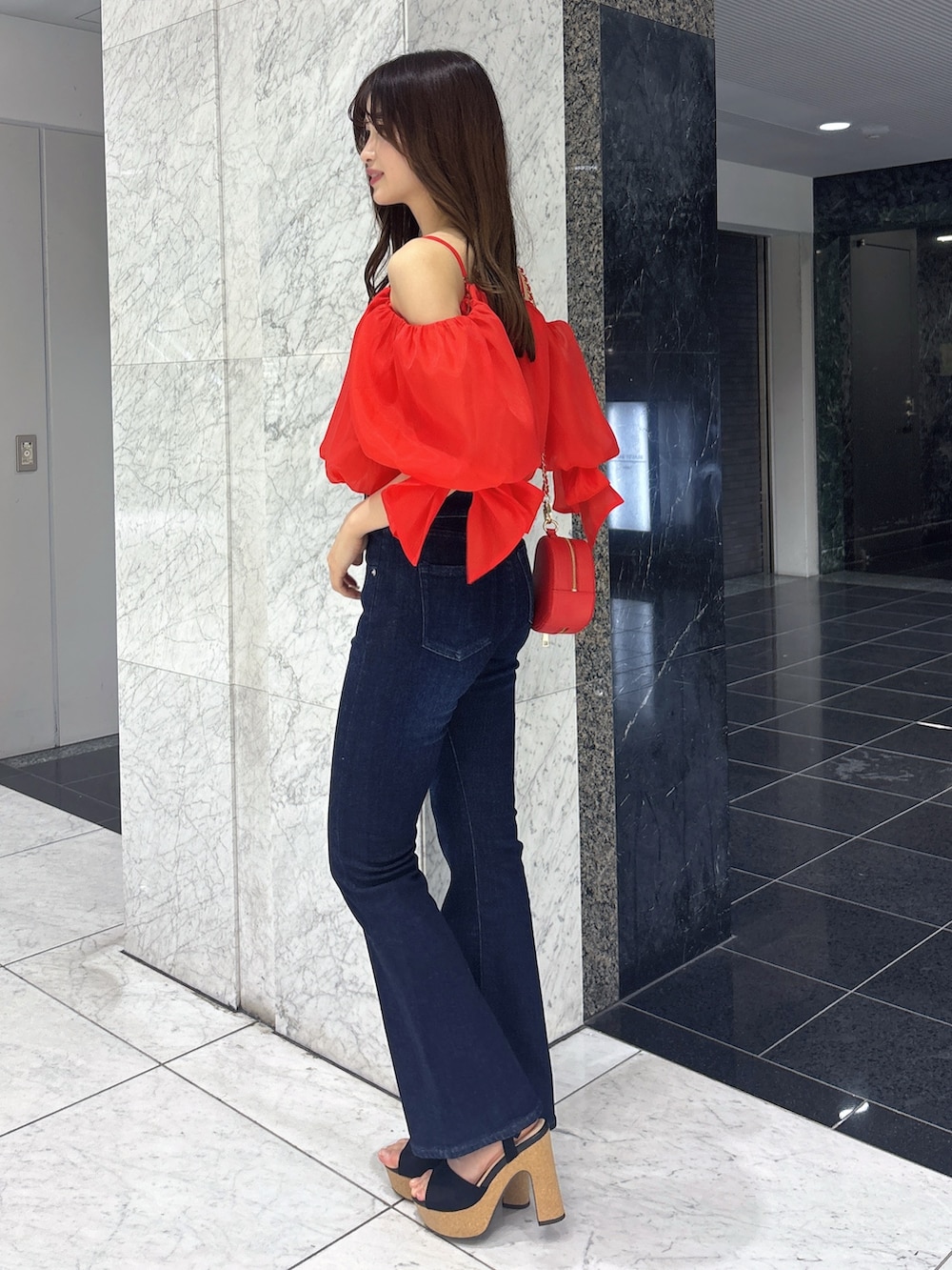 ブルー系のデニムパンツ、レッド系のシャツ/ブラウス、レッド系のショルダーバッグを着用したレディースの春コーディネートの3枚目の写真