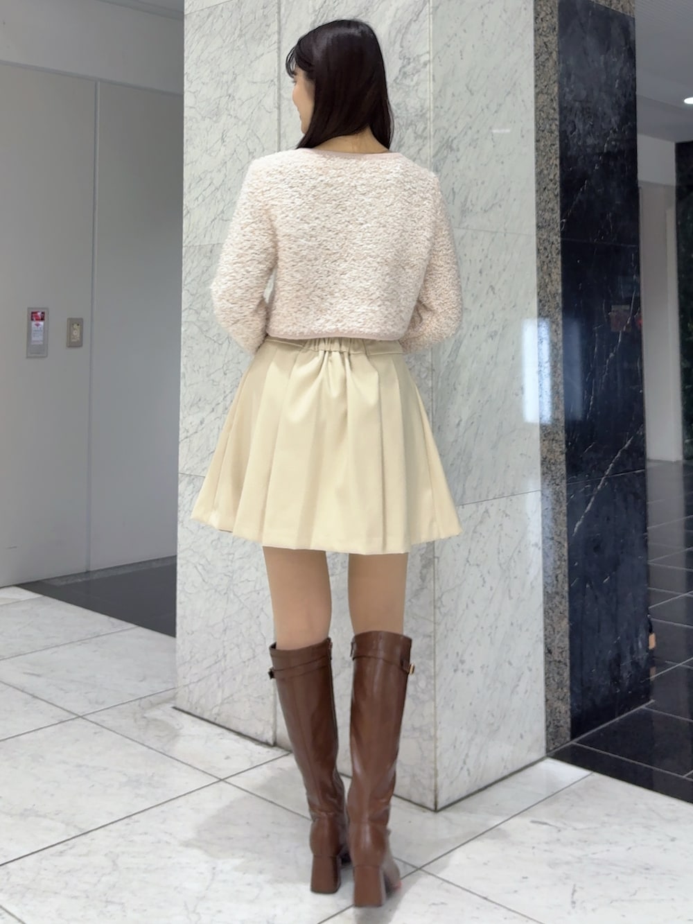 ホワイト系のスカート、ピンク系のノーカラージャケット、ブラウン系のブーツを着用したレディースの冬コーディネートの4枚目の写真