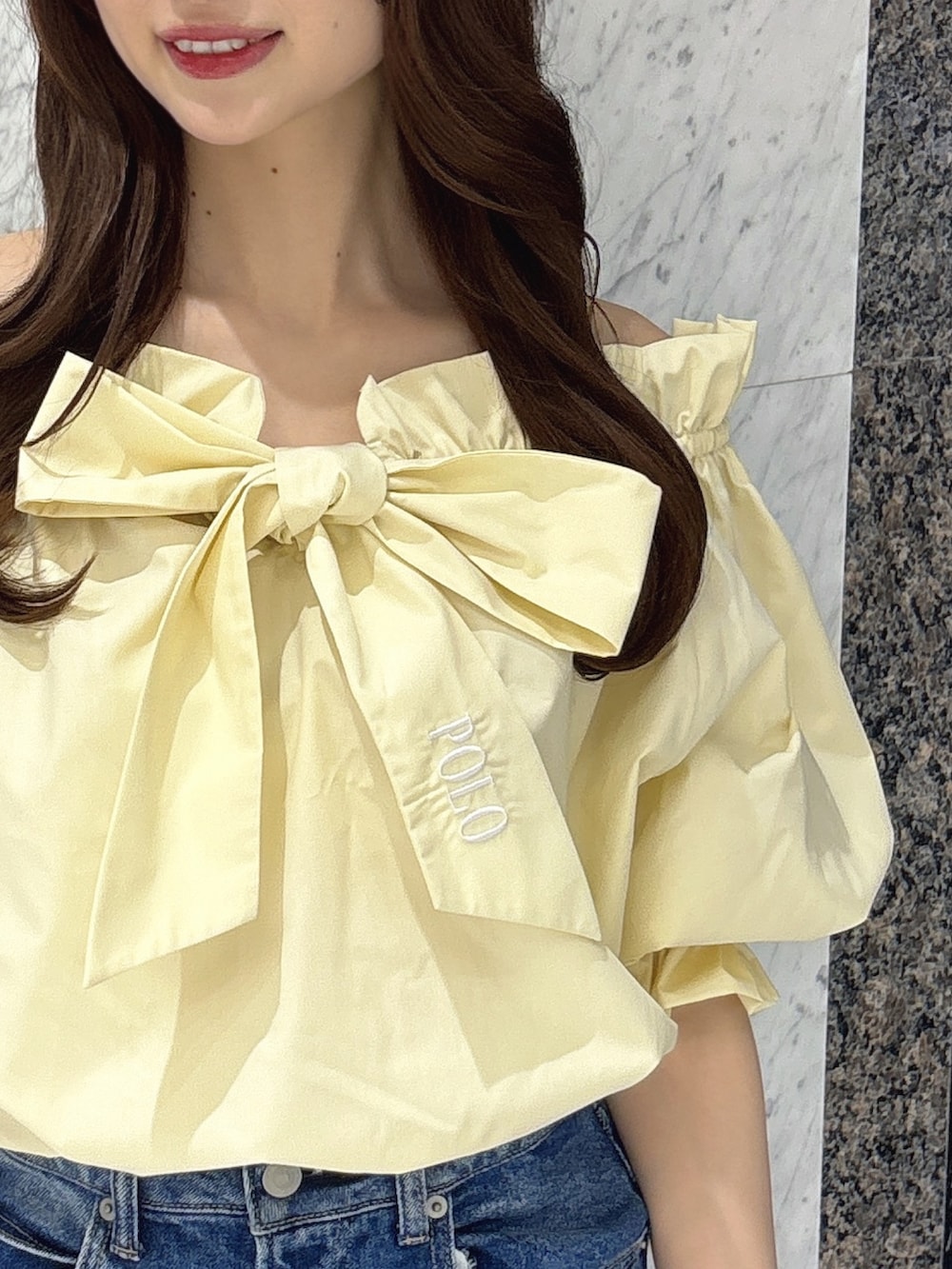 ブルー系のデニムパンツ、イエロー系のシャツ/ブラウス、ホワイト系のパンプスを着用したレディースの春コーディネートの5枚目の写真