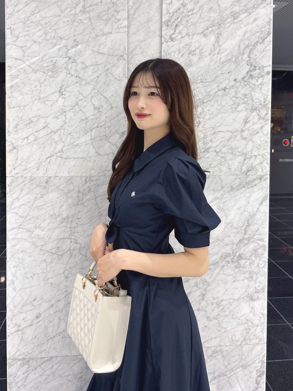 ブルー系のワンピース、ホワイト系のハンドバッグ、ブラック系のパンプスを着用したレディースの春コーディネートの6枚目の写真