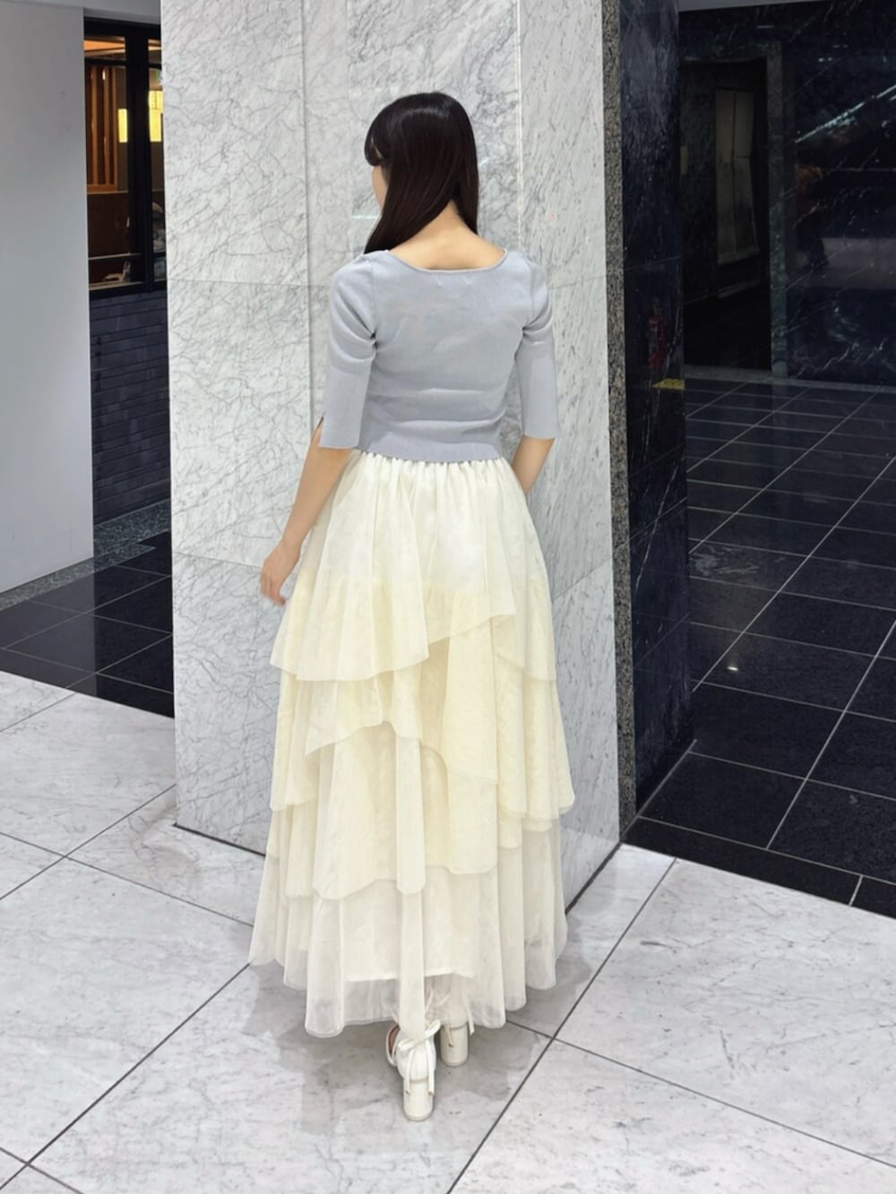 ホワイト系のスカート、グレー系のニット/セーター、ホワイト系のパンプスを着用したレディースの夏コーディネートの4枚目の写真