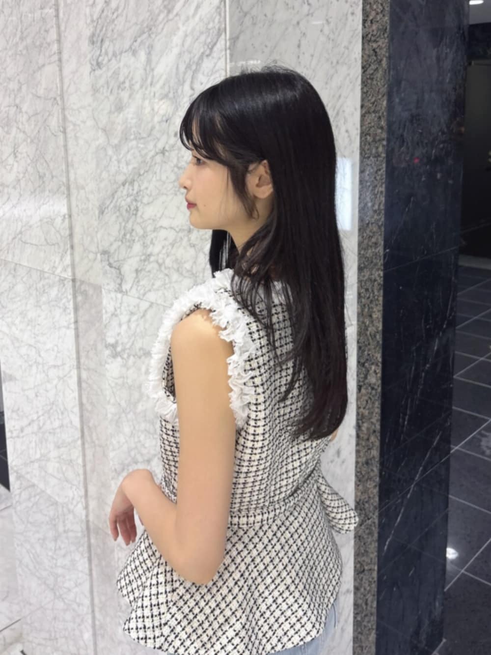 ブラック系のサンダル、ホワイト系のベスト、ブルー系のデニムパンツを着用したレディースの夏コーディネートの5枚目の写真