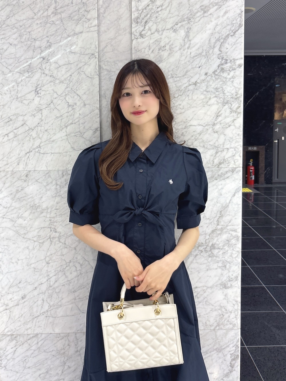 ブルー系のワンピース、ホワイト系のハンドバッグ、ブラック系のパンプスを着用したレディースの春コーディネートの5枚目の写真