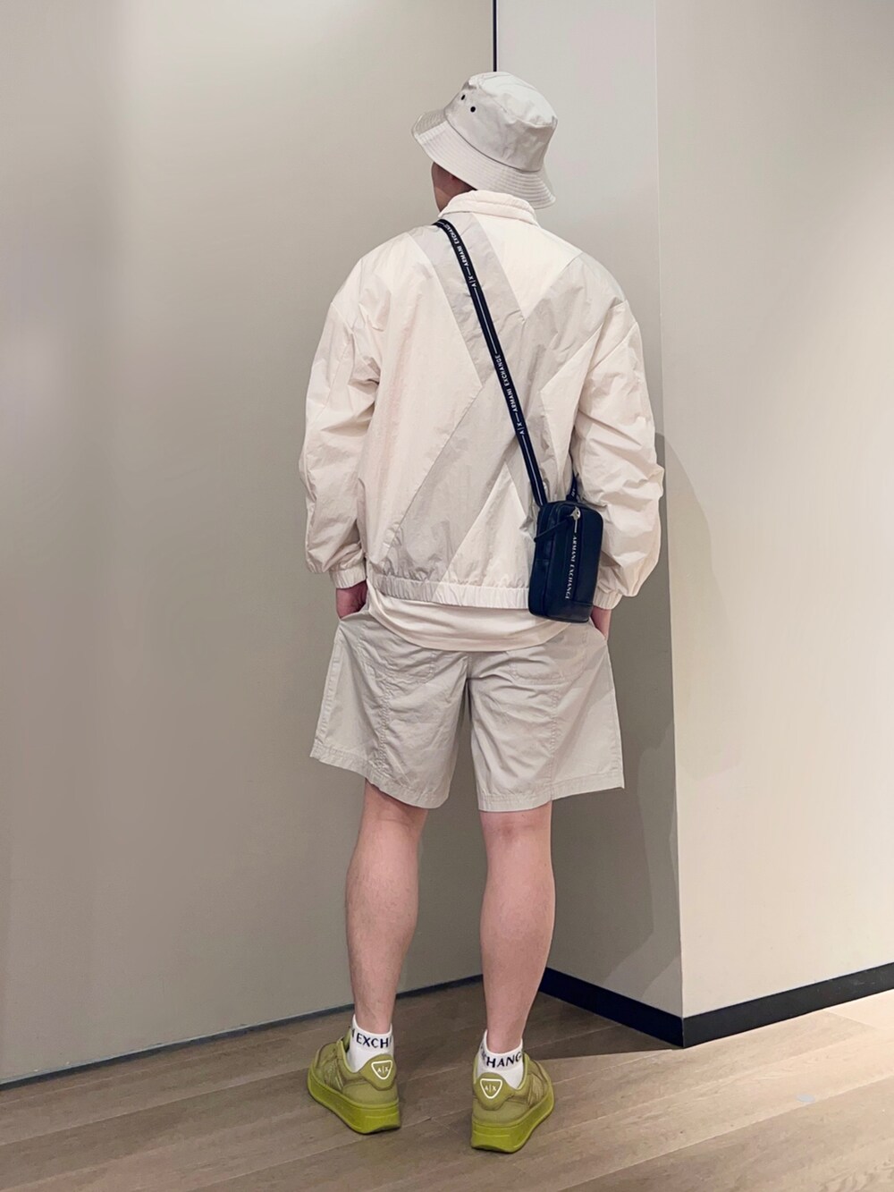 イエロー系のスニーカー、ホワイト系のTシャツ/カットソー、ベージュ系のナイロンジャケットを着用したメンズの春コーディネートの2枚目の写真