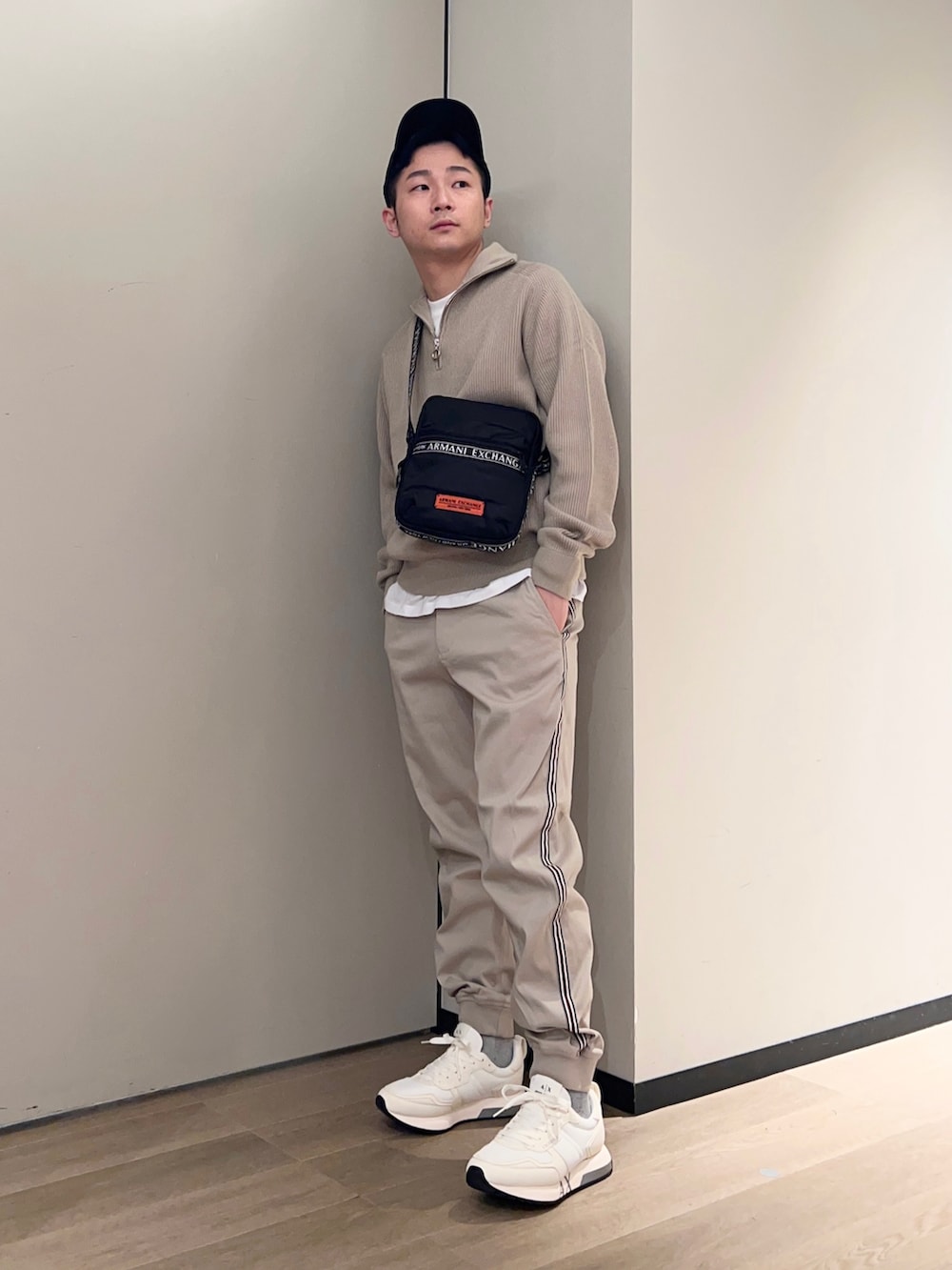 ブラック系のショルダーバッグ、ホワイト系のTシャツ/カットソー、ベージュ系のニット/セーターを着用したメンズの秋コーディネートの2枚目の写真