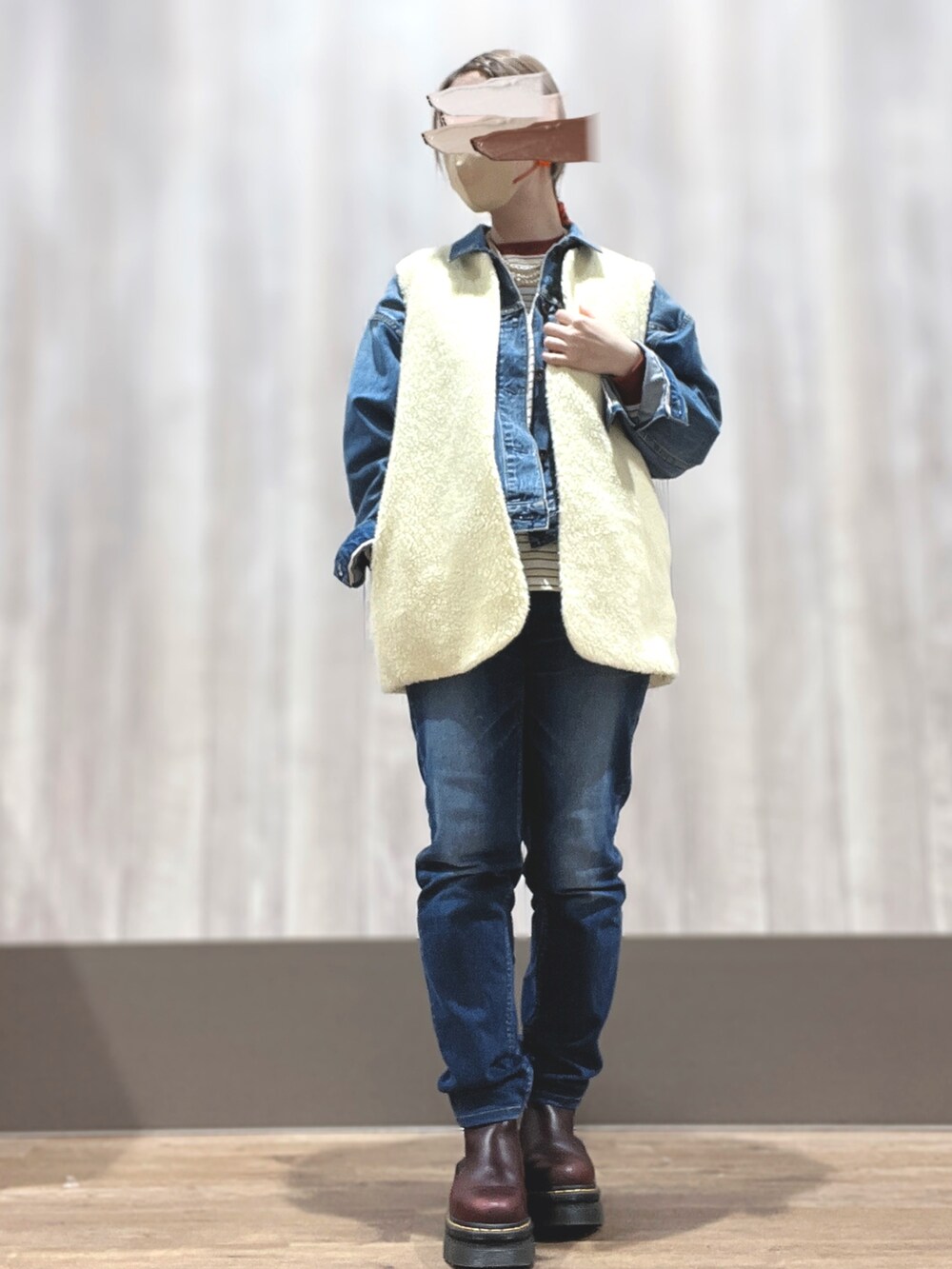 ブラウン系のブーツ、ブルー系のデニムパンツ、ホワイト系のベストを着用したレディースの冬コーディネートの2枚目の写真