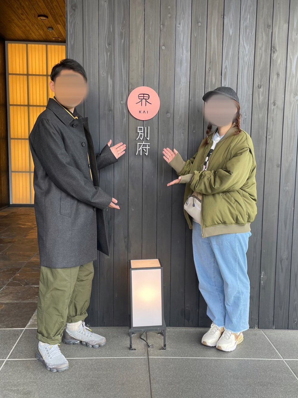 グレー系のノーカラーコート、グリーン系のカーゴパンツ、グレー系のスニーカーを着用したメンズの冬コーディネートの2枚目の写真
